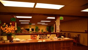 A reception area with a wooden counter, potted plants, and a green exit sign. - Wells Chinatown (Wells)