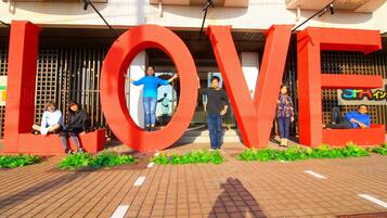 A building entrance with large red letters spelling "LOVE" and people sitting and standing in front.