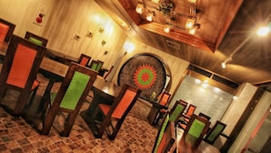 A restaurant interior with wooden tables and chairs, a patterned wall, and a decorative ceiling light fixture. - Spa Inn Shirahama (Shirahama)