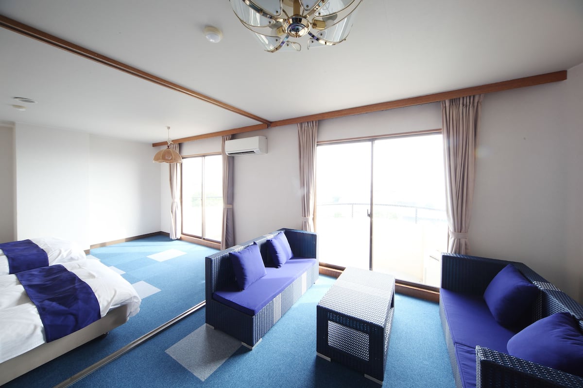 A hotel room with two sofas, a small table, and a ceiling fan.