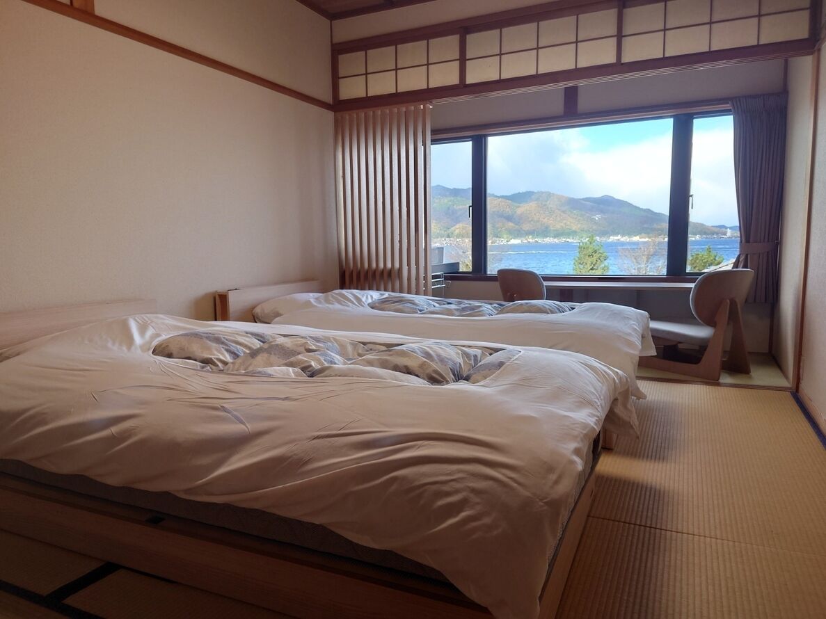 Ett hotellrum med två sängar, havsutsikt och en traditionell japansk inredning.