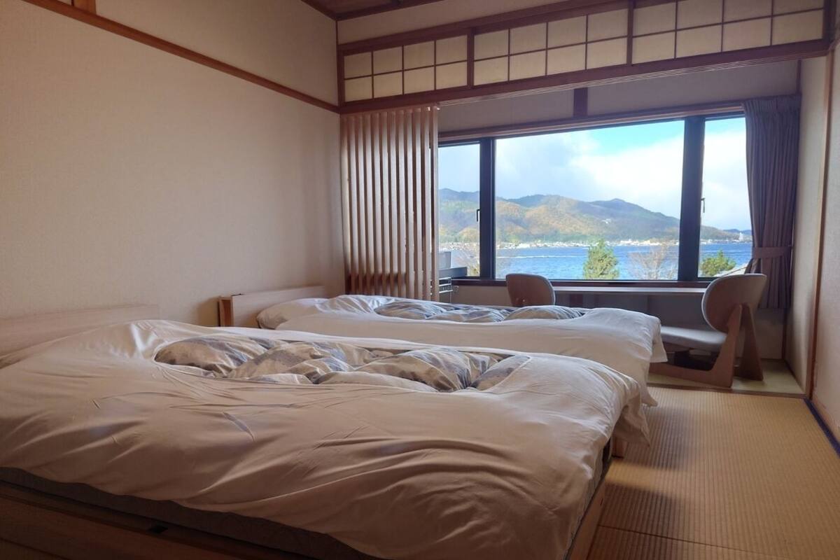 Ett hotellrum med två sängar, havsutsikt och en traditionell japansk inredning.