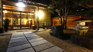 A traditional Japanese building with a tiled entrance, potted plants, and a stone lantern. - Jinpuso (Miyazu)
