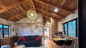 A cozy living room with a dark sofa, a wooden coffee table, and a large window. - The River Lodge (Ohakune)