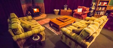 Ein gemütliches Wohnzimmer mit gestreiften Sofas, einem Holztisch, einem Kamin und einem Bücherregal.