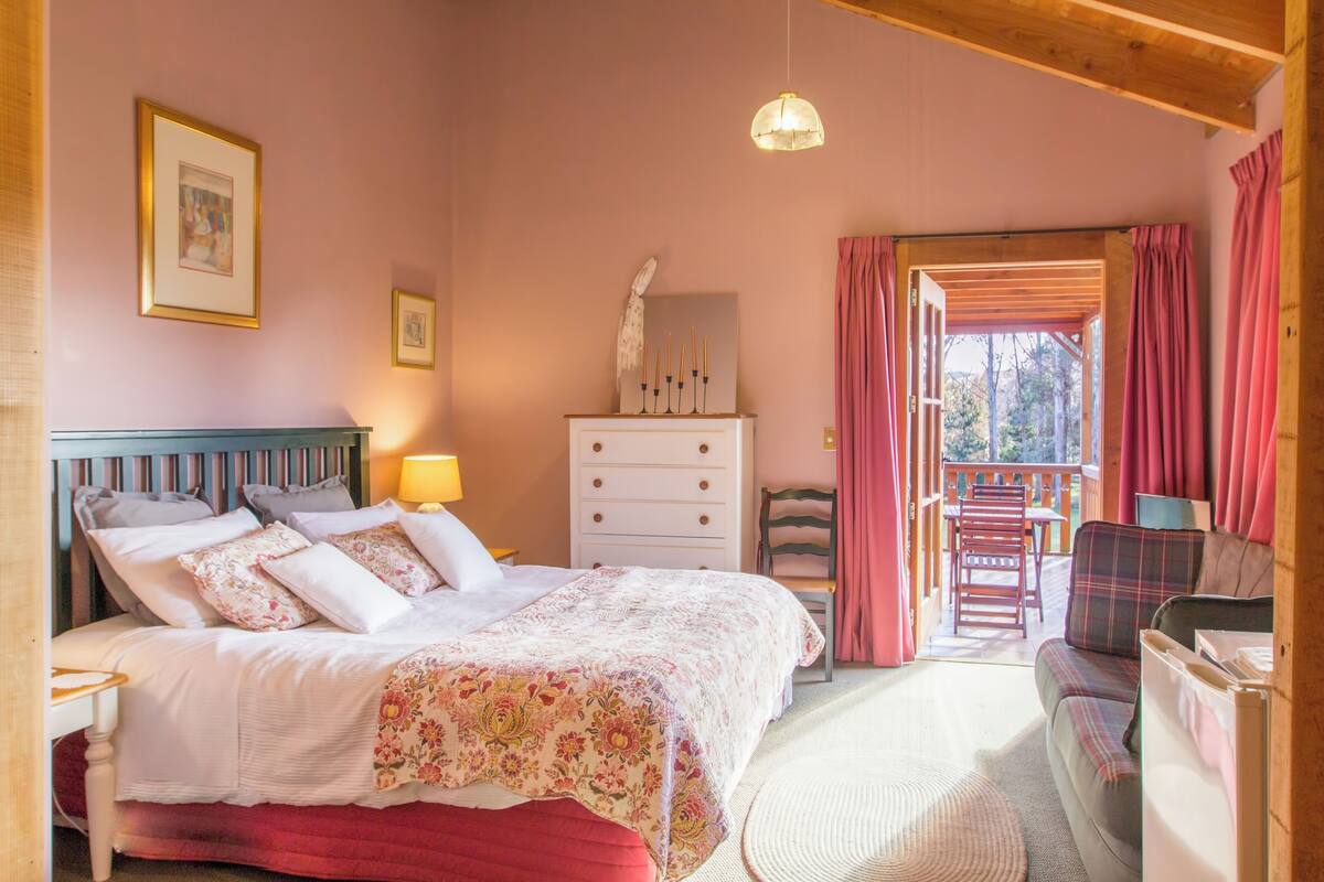 Un dormitorio con cama, cómoda, silla y vista al exterior.