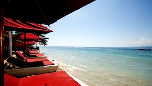 A beachside seating area with red cushions and umbrellas, overlooking the sea. - Bel Air Resort & Spa (Gili Air)