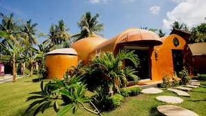A modern building with a dome-shaped structure, surrounded by lush greenery and palm trees. - Bel Air Resort & Spa (Gili Air)