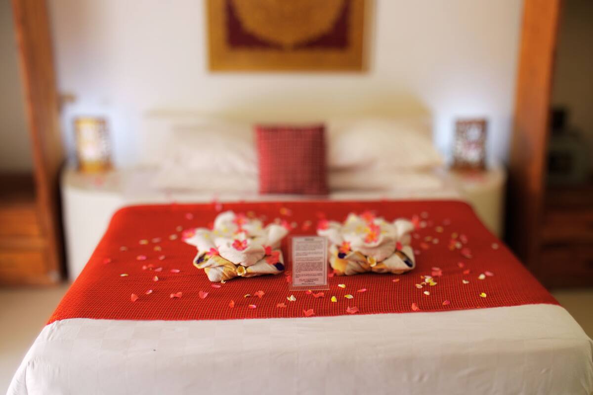 A neatly made bed with a red bedspread, a pillow, and a small decorative item on the bed.
