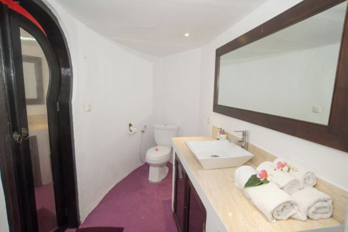 Un bagno con un water bianco, un lavandino con uno specchio sopra e asciugamani sul mobile.