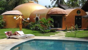 A pool area with lounge chairs and a unique building with golden domes. - Bel Air Resort & Spa (Gili Air)