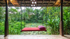 A hammock swing with a red cushion in a lush garden with a pond. - Apa Villa Illuketia (Padinnoruwa)