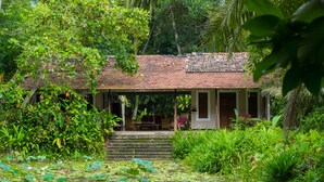 A traditional building with a tiled roof, surrounded by lush greenery and a pond with lily pads. - Apa Villa Illuketia (Padinnoruwa)