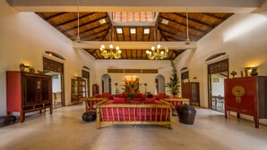 A spacious room with a high ceiling, a central seating area with a red sofa, and a large chandelier. - Apa Villa Illuketia (Padinnoruwa)
