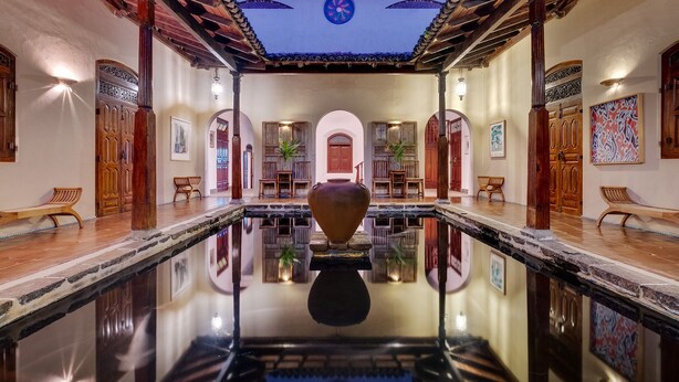 A spacious indoor pool with a central decorative vase, wooden benches, and a tiled ceiling. - Apa Villa Illuketia (Padinnoruwa)