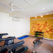 A gym with exercise equipment, a wall with motivational text, and a ceiling fan.