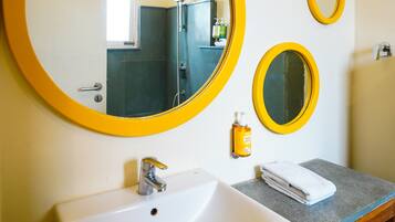 Un baño con un espejo grande, un espejo más pequeño, un lavabo y un dispensador de jabón para manos.