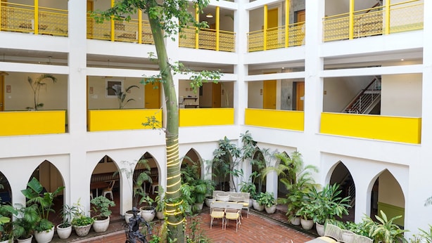 Ein mehrgeschossiges Atrium mit gelben Balkonen, Pflanzkübeln und Sitzgelegenheiten im Freien.