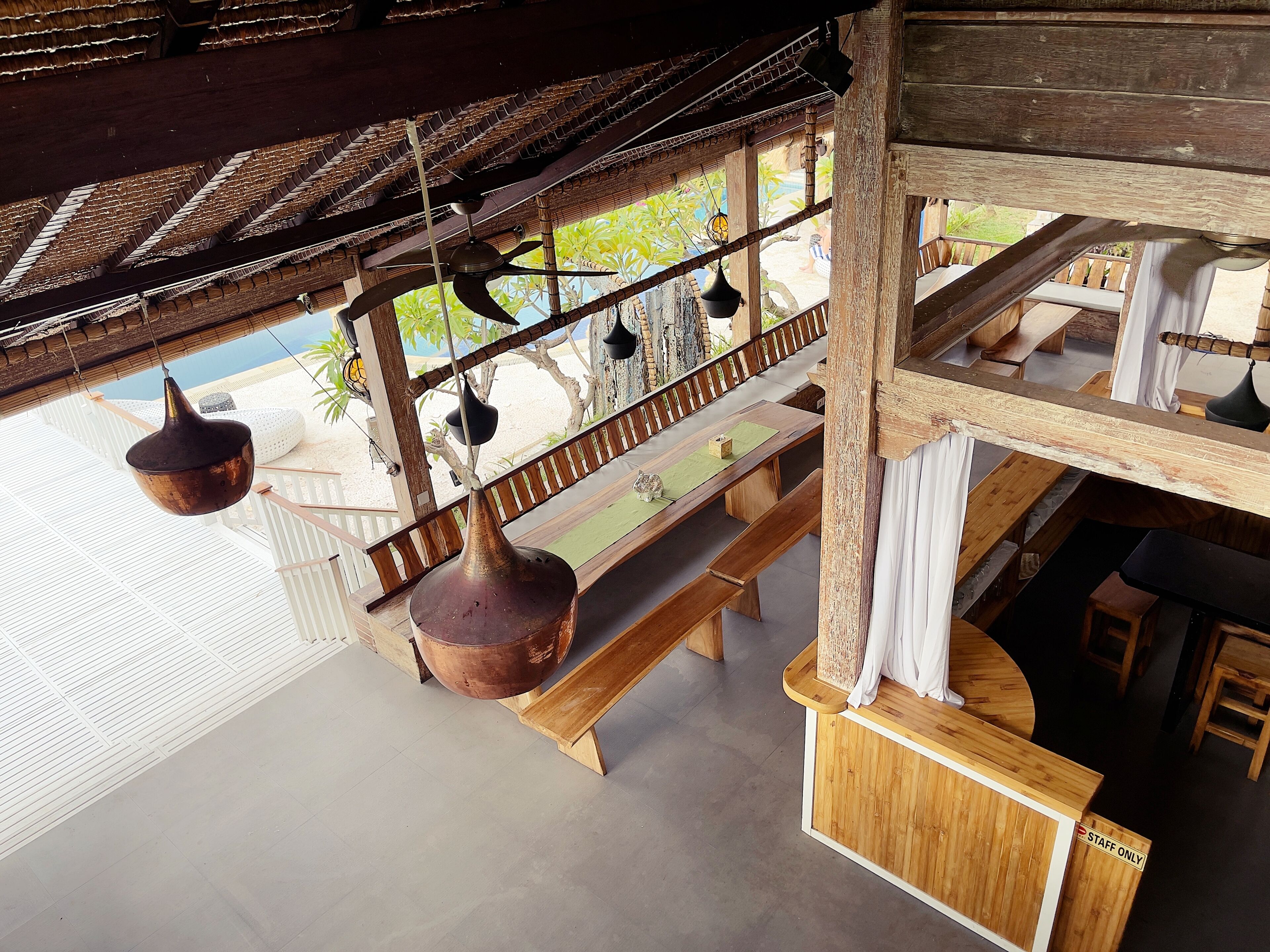 A wooden outdoor seating area with a bench and hanging planters.