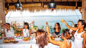 Un grupo de personas brindando en una mesa con vista al mar.