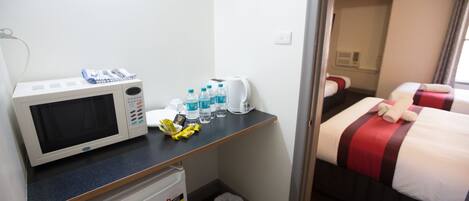 A hotel room with a microwave, mini-fridge, and a small table with toiletries.