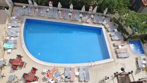 Ein Luftbild eines Swimmingpools, umgeben von Liegestühlen und Tischen.
