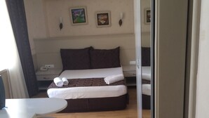 Ein kleines Hotelzimmer mit einem Einzelbett, einem Schreibtisch und einem Stuhl.