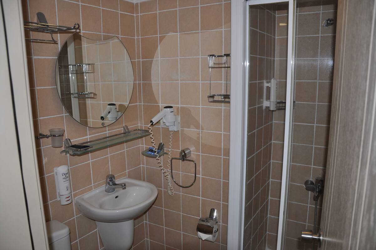 A bathroom with a sink, mirror, and shower area.