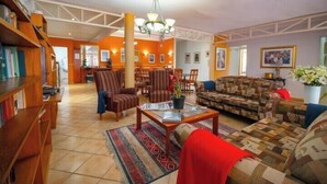 A spacious lobby with a central dining area, multiple seating options, and a large chandelier. - Broadway Guesthouse (Cape Town)