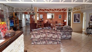 A spacious living area with a large sofa set, a dining table, and a kitchen in the background. - Broadway Guesthouse (Cape Town)