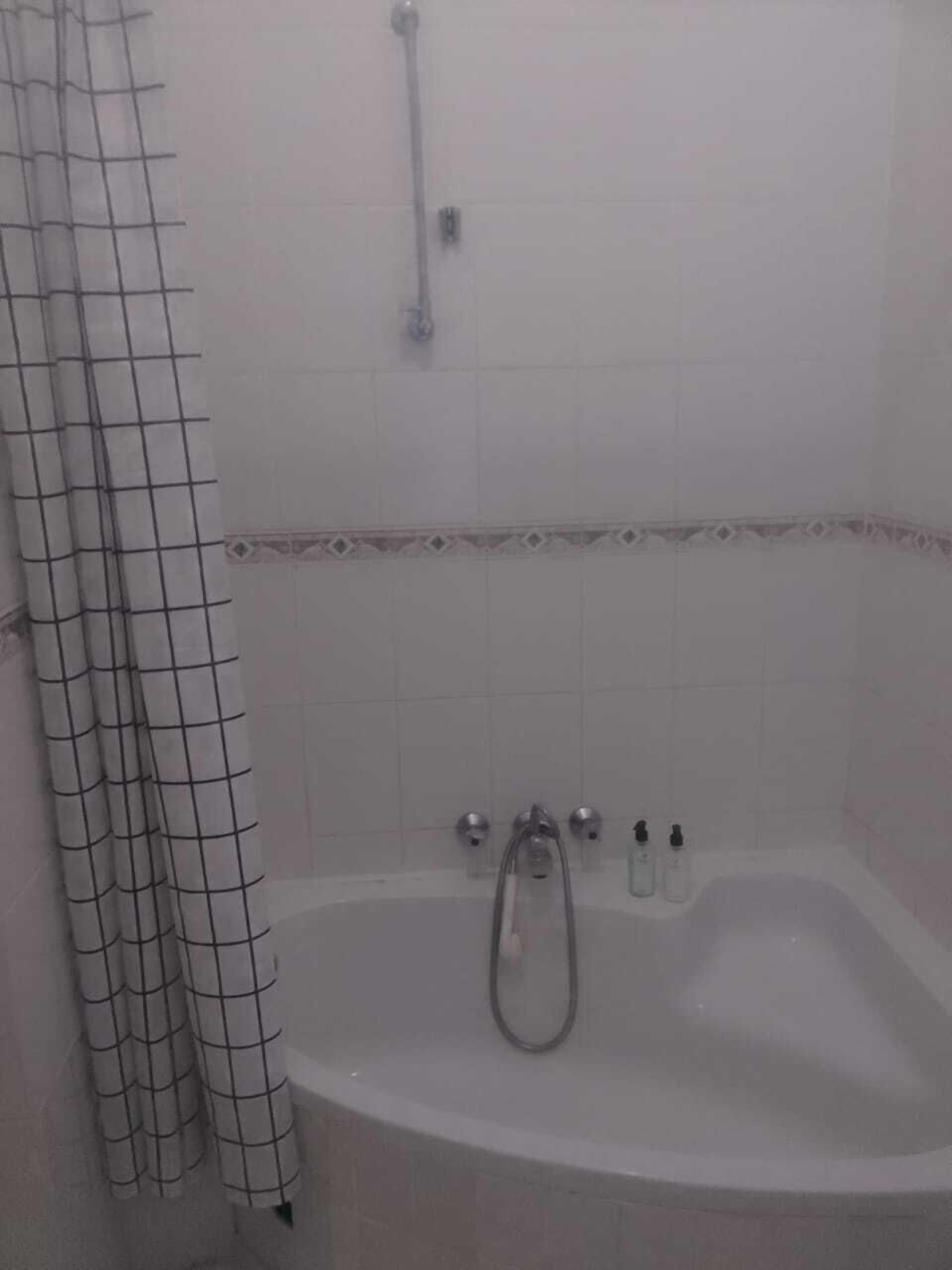 Un bagno con una vasca, una doccia e una parete rivestita di piastrelle.