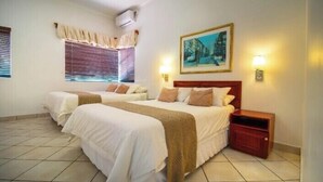 A hotel room with two beds, a painting on the wall, and a nightstand. - Broadway Guesthouse (Cape Town)