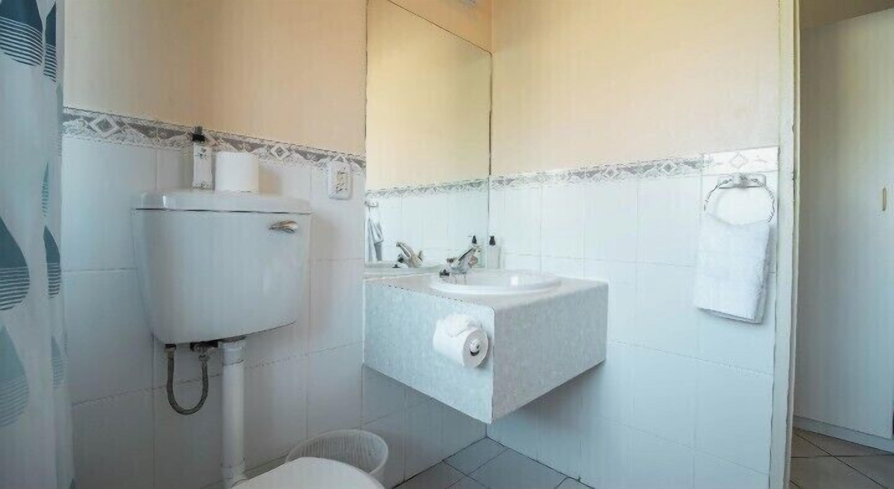 Un baño con inodoro, lavamanos y espejo.