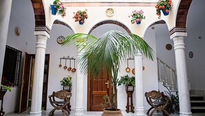 Un patio con una puerta de madera, columnas blancas y plantas en macetas.