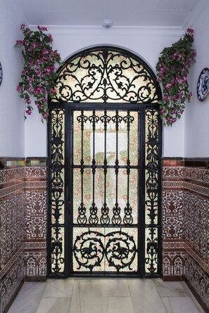 A black wrought iron gate with intricate designs and a decorative glass panel.