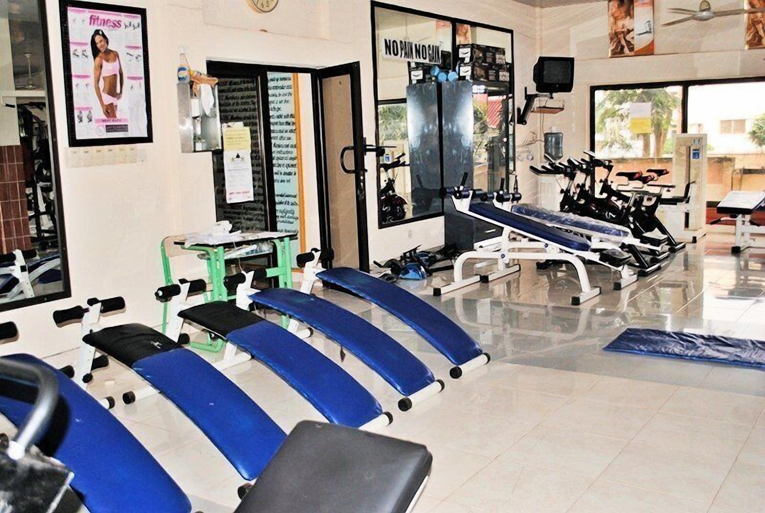 Un gimnasio con equipo de ejercicio, un espejo y un cartel en la pared.