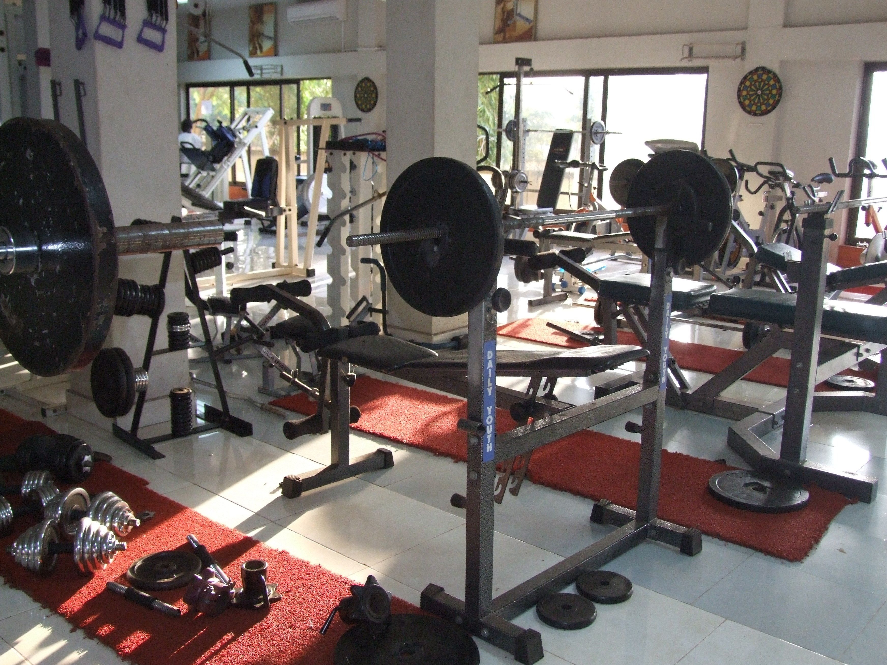 Een fitnessruimte met gewichthefapparatuur, loopbanden en trainingsmachines.