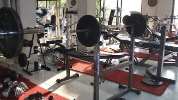 Een fitnessruimte met gewichthefapparatuur, loopbanden en trainingsmachines.