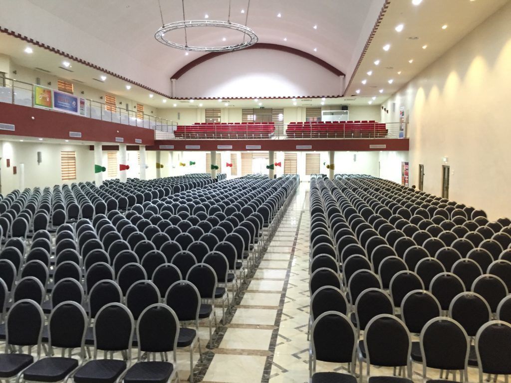A large hall with rows of chairs and a balcony with red seats.
