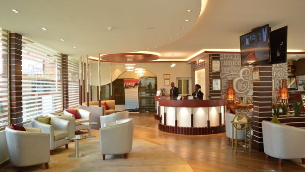 A hotel lobby with a reception desk, seating area, and a TV mounted on the wall. - Eusbett Hotel (Sunyani)