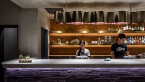 A bar area with a marble countertop, shelves with bottles, and a decorative ceiling. - Estinate Hotel Naha (Naha)