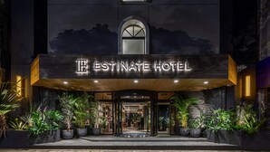 The exterior of the ESTINATE HOTEL with a prominent illuminated sign, large potted plants, and a modern architectural design. - Estinate Hotel Naha (Naha)