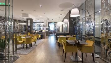 A modern restaurant with yellow chairs and tables, a bar area, and decorative wall panels.