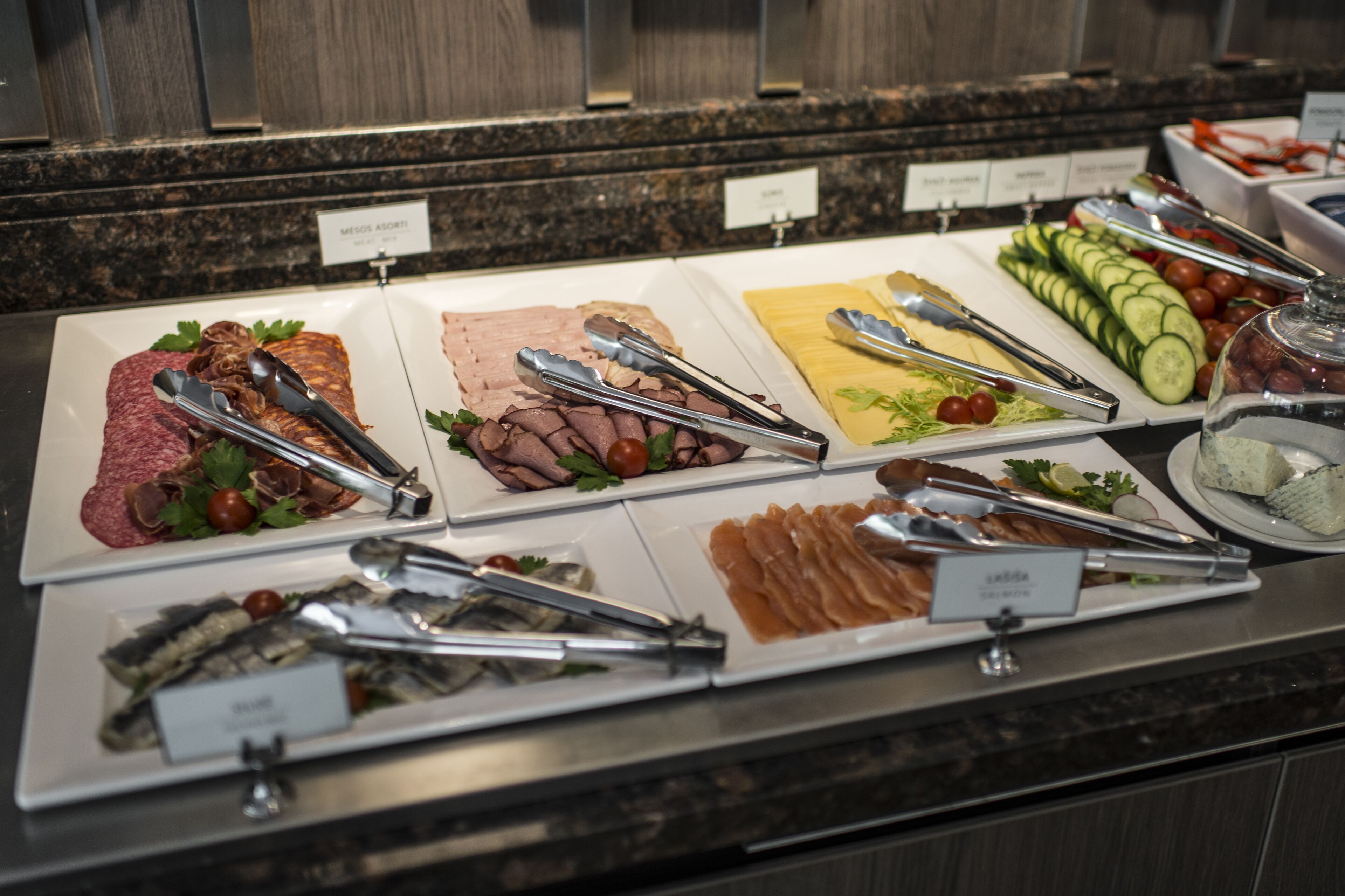 A buffet with various food items including meats, cheeses, and vegetables.