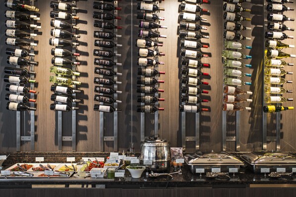 A wine rack with various bottles, a buffet area with food and condiments, and a coffee station. - Hotel Congress Avenue (Vilnius)