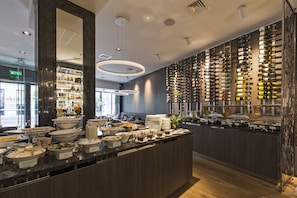 A modern hotel bar with a wine wall, buffet with various food options, and a large mirror. - Hotel Congress Avenue (Vilnius)