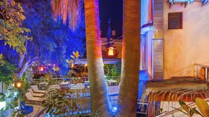 A well-lit outdoor area with palm trees, a pool, and lounge chairs.