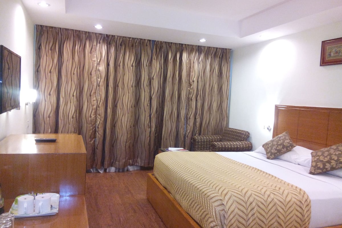 A hotel room with a bed, bedside table, and a mirror.