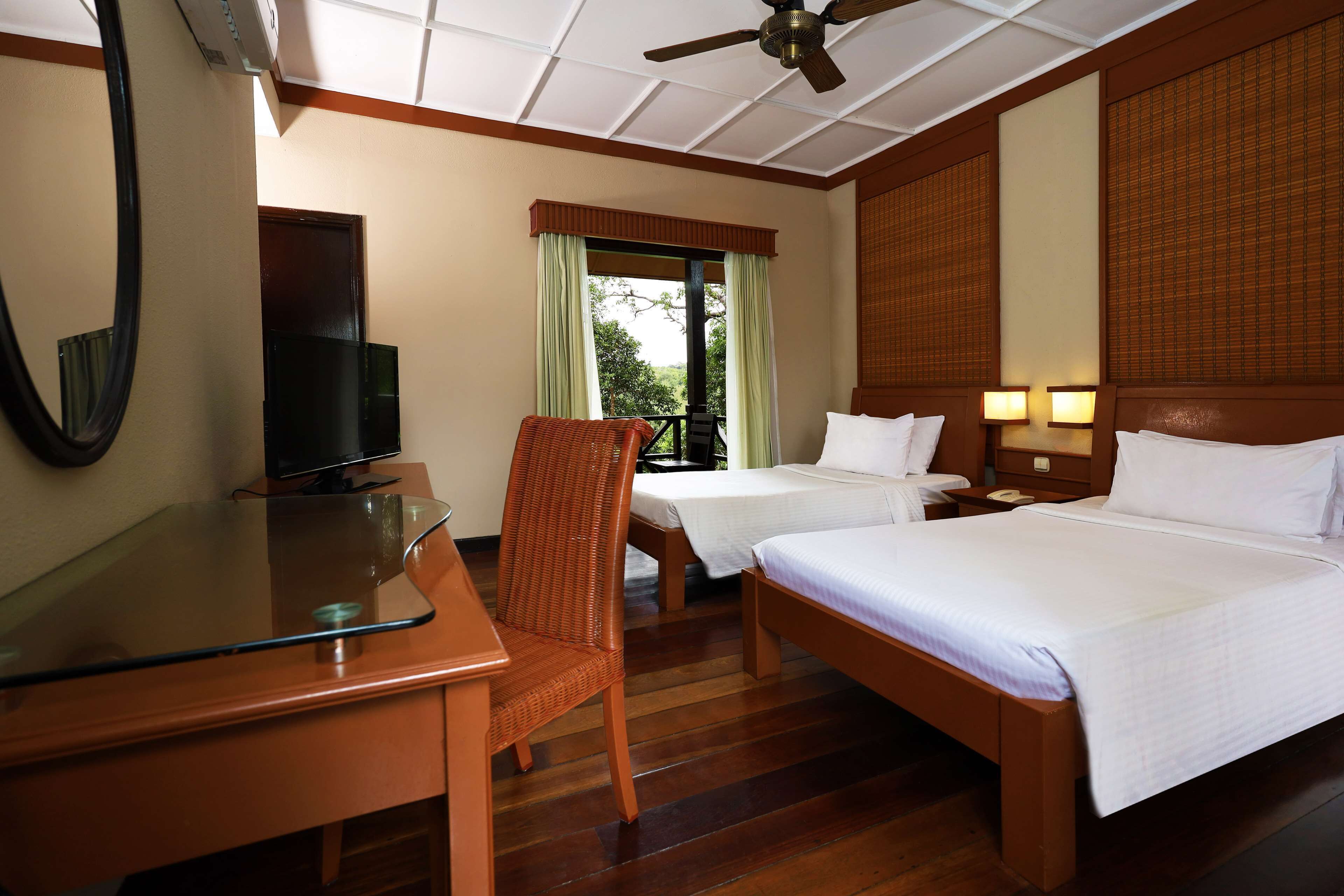 A hotel room with a bed, a desk, a chair, a television, and a window with curtains.