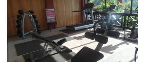A gym with exercise equipment, a bench, and a treadmill.